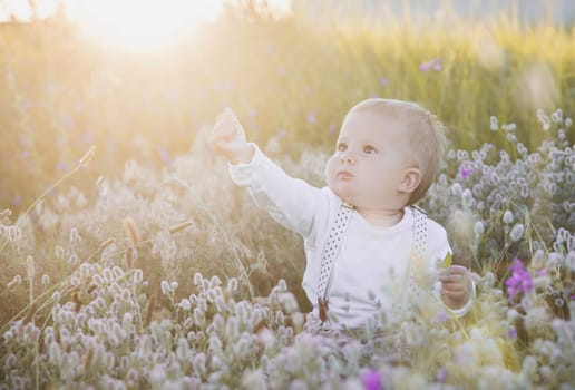 blond baby in cowboy costume in the field.