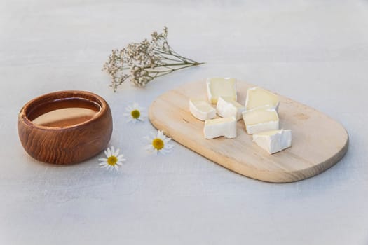 Blue cheese on a wooden plank, honey and flowers.