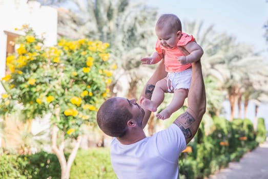 father holding adorable child at home in the garden.