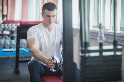 Athlete pulls a load, training his back in the gym.