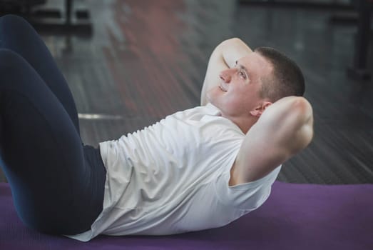 Athlete trains abdominal muscles on the floor in the gym.