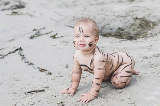 beautiful naked baby got dirty with mud walking on the beach.