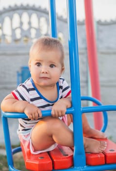 Blonde baby on a swing at sunset.