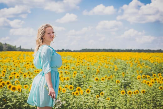 Attractive blonde in a blue dress in a field of sunflowers.