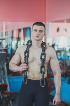 an athlete stands in a gym with a large chain around his neck.