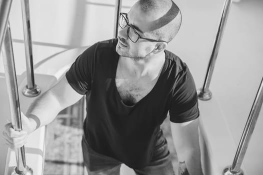 man in glasses steps of a yacht and looks left thoughtfully.