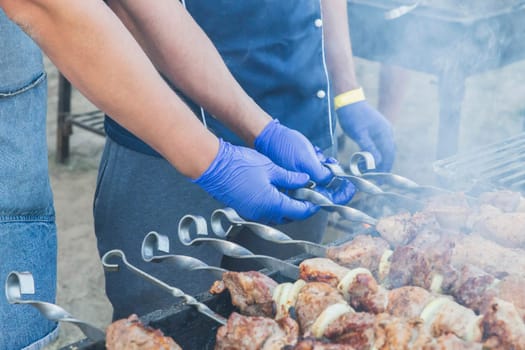 two cooks in sterile gloves are grilling meat.