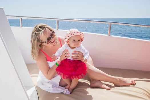 mom with newborn daughter sunbathe on a yacht in the sea.