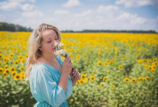 Attractive blonde in a blue dress in a field of sunflowers.