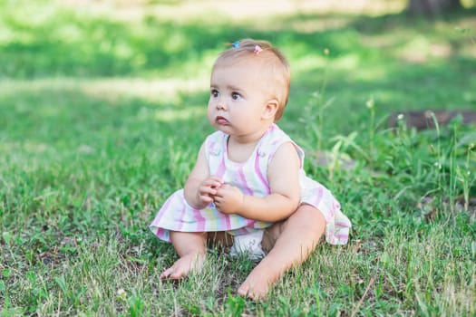 adorable baby in multicolored dress in the park.