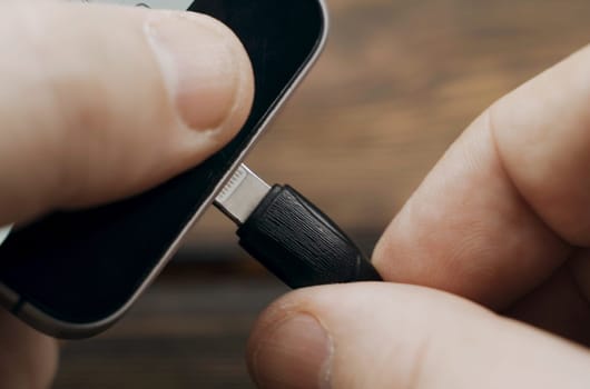 Close-up of connecting charging to the phone. Phone charging by wire.