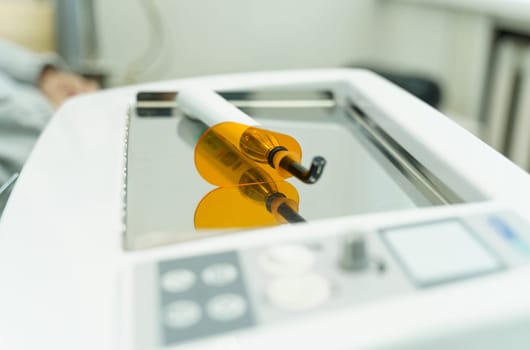 On the mirror surface lies a device for filling and drying teeth - a dental polymerization lamp.