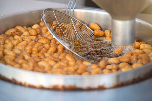 The process of cooking lokma, the cook cooks lokma in a deep fryer. Industrial production of a popular Middle Eastern dessert made from deep-fried dough balls. Little donuts