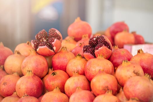 Pomegranates on the market. On the counter stacked fresh ripe pomegranates cut into pieces. Cracked pomegranate. Ripe pomegranate closeup.