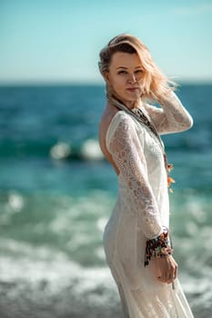 Woman beach sea white dress. The middle-aged looks good with blonde hair, boho style in a white long dress with beach decorations on the neck and arms