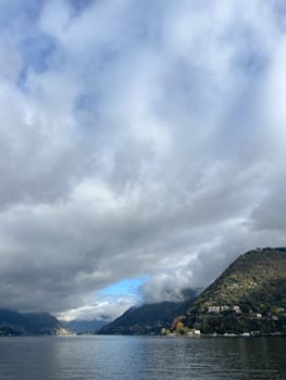 White cumulus clouds envelop a mountain range by the sea. High quality photo