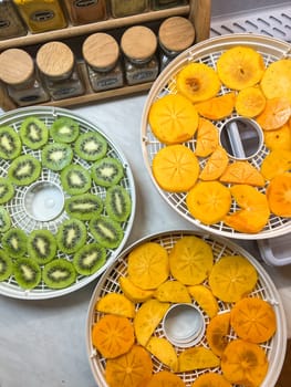 Sliced kiwi and persimmon lie on drying trays on the table. High quality photo