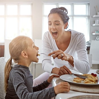 Open up my wide...a mother and daughter having breakfast at home