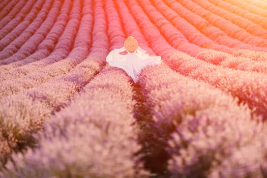 Happy woman in a white dress and straw hat strolling through a lavender field at sunrise, taking in the tranquil atmosphere