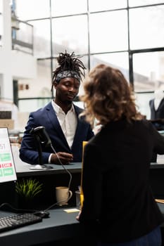 African american customer talking with store manager at cash register, discussing sale cupon during shopping session in boutique. Stylish client buying fashionable clothes, commercial activity concept