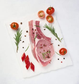 Raw pork tenderloin on the bone and spices on a white background. Portion for lunch and dinner, top view