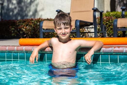 Concept of fun, health and vacation. Oudoor summer activity. Boy eight years old sits in a pool in hot summer day.