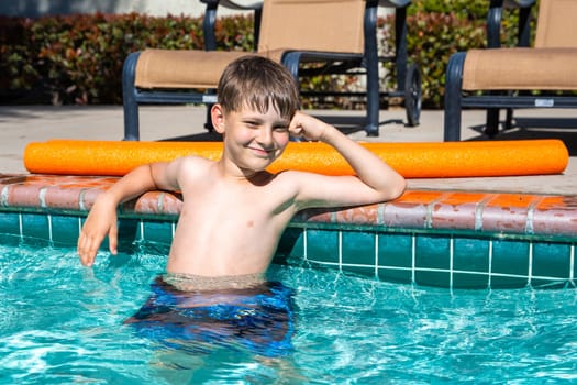 Concept of fun, health and vacation. Oudoor summer activity. Boy eight years old sits in a pool in hot summer day.