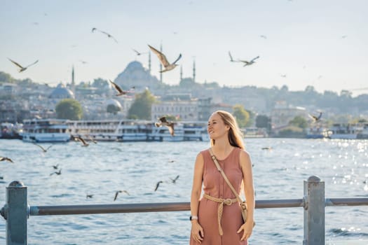 Young woman traveler in pinc dress enjoying great view of the Bosphorus and lots of seagulls in Istanbul.