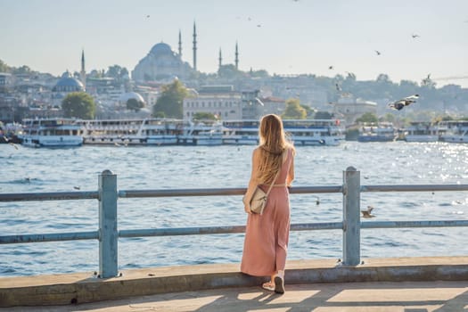 Young woman traveler in pinc dress enjoying great view of the Bosphorus and lots of seagulls in Istanbul.