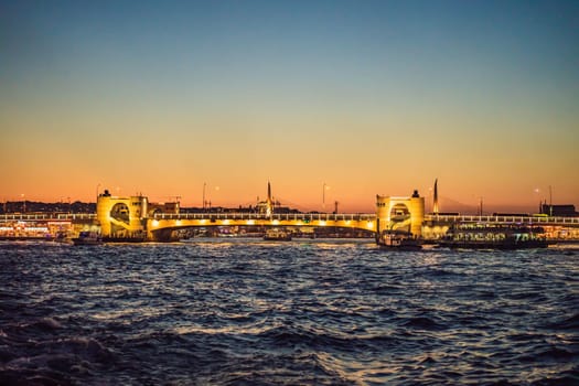 Istanbul at sunset, Turkey. Tourist boat sails on Golden Horn in summer. Beautiful sunny view of Istanbul waterfront with old mosque. Concept of travel, tourism and vacation in Istanbul and Turkey. Turkiye.