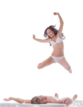 Cheerful slim woman jumping into bed with sexy guy, isolated on white