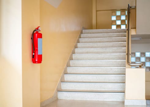 A fire extinguisher hangs up the stairs. Fire safety concept.