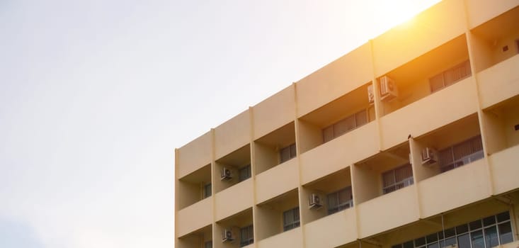 side view of yellow concrete building Intersect the orange sun.