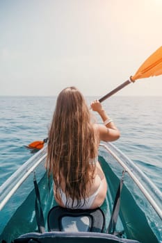 Woman in kayak back view. Happy young woman with long hair floating in transparent kayak on the crystal clear sea. Summer holiday vacation and cheerful female people having fun on the boat.