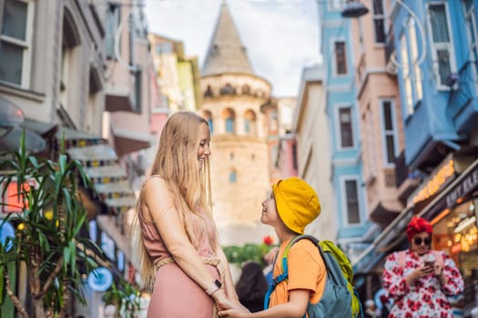 Portrait of beautiful mother and son tourists with view of Galata tower in Beyoglu, Istanbul, Turkey. Turkiye. Traveling with kids concept.