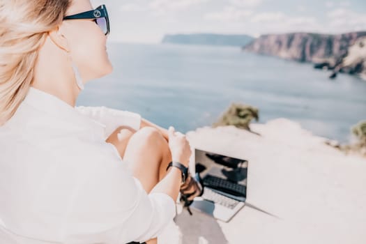 Happy girl doing yoga with laptop working at the beach. beautiful and calm business woman sitting with a laptop in a summer cafe in the lotus position meditating and relaxing. freelance girl remote work beach paradise