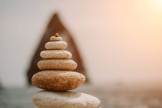 Pyramid stones on the seashore with warm sunset on the sea background. Happy holidays. Pebble beach, calm sea, travel destination. Concept of happy vacation on the sea, meditation, spa, calmness.