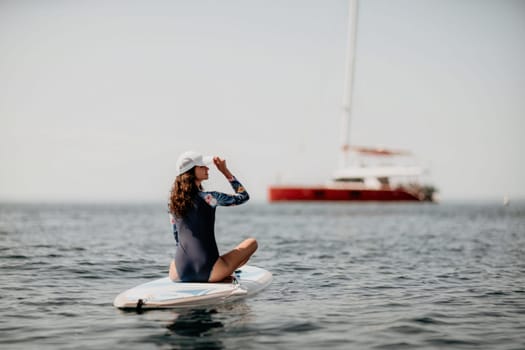 Woman sup yoga. Middle age sporty woman practising yoga pilates on paddle sup surfboard. Female stretching doing workout on sea water. Modern individual hipster outdoor summer sport activity