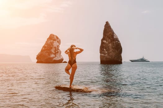 Woman meditating in yoga pose silhouette at the ocean, beach and rock mountains. Motivation and inspirational fit and exercising. Healthy lifestyle outdoors in nature, fitness concept.