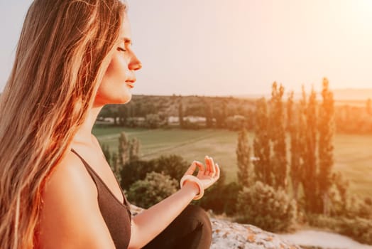 Well looking middle aged woman with long hair, fitness instructor in leggings and tops doing stretching and pilates on the rock near forest. Female fitness yoga routine concept. Healthy lifestyle.