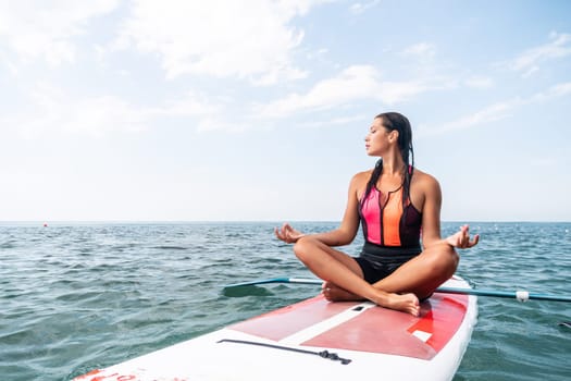 Woman sup yoga. Happy young sporty woman practising yoga pilates on paddle sup surfboard. Female stretching doing workout on sea water. Modern individual female outdoor summer sport activity