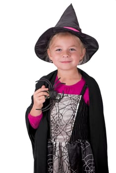 a girl in a halloween costume holds a black toy spider in her hands on a white background