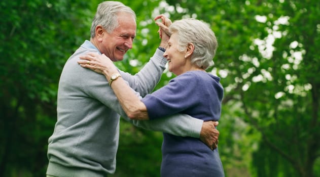 Romance turns the grey years into the great years. a happy senior couple dancing in the park