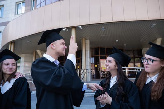 Happy students in graduate gown communicate in sign language