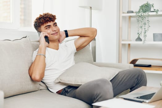 man interior blogger mobile lifestyle blissful sofa curly young internet cell smile communication selfies person male