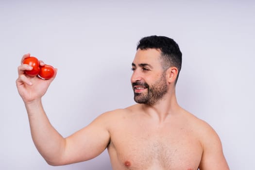 Full isolated studio picture from a young naked man with underwear and tomatoes