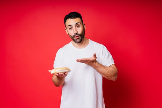 Man with freshly baked bread in hands isolated on red background studio