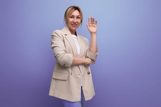 positive blond young business woman in jacket smiling on studio background.