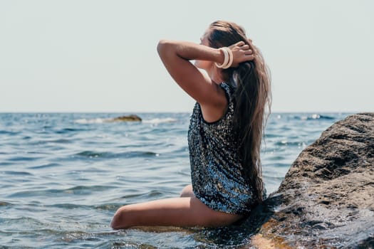 Woman travel sea. Young Happy woman in a long red dress posing on a beach near the sea on background of volcanic rocks, like in Iceland, sharing travel adventure journey