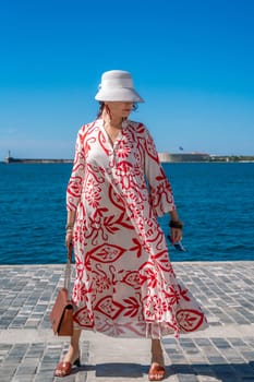 woman in a hat and dress enjoys the blue sea and summer. Welcome summer